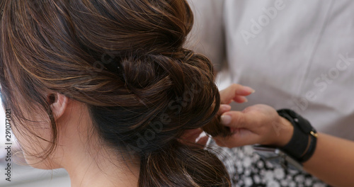 Hairdresser creating a hairstyle for bride in salon