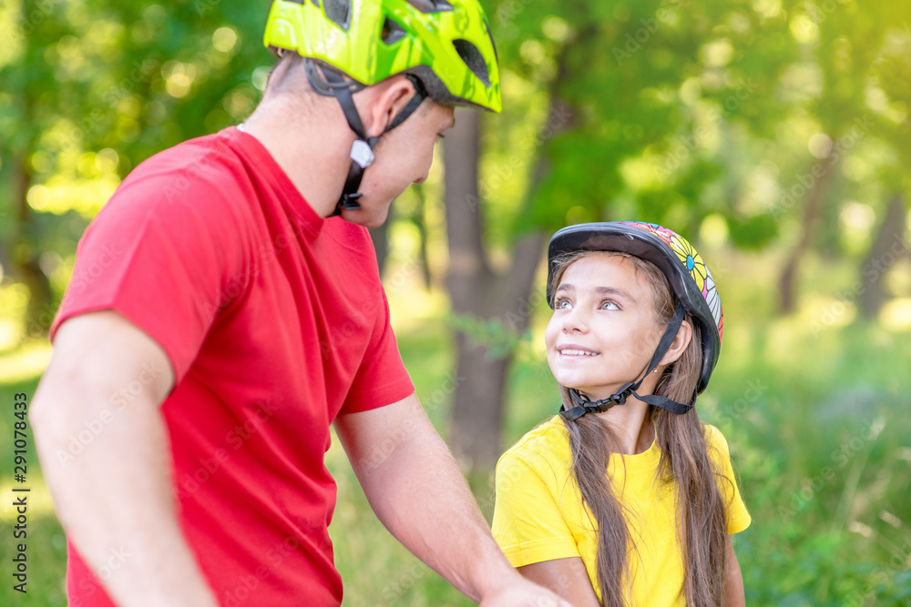 Naklejka premium Father communicates with his daughter, teaching her how to ride a bicycle