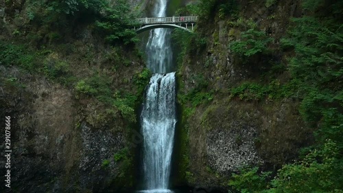 Bottom up tilt of a rocky cliff and free falling water of Multnomah waterfall photo