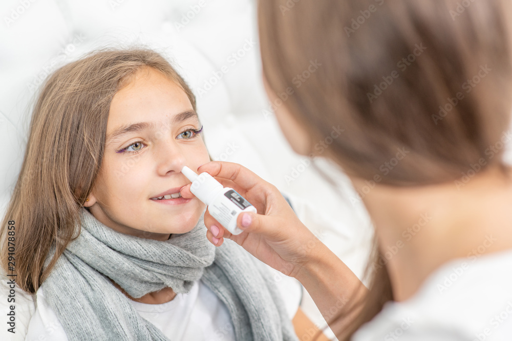 Mother using nose spray to cure her teen girl at home Mother using nose spray to cure her teen girl at home
