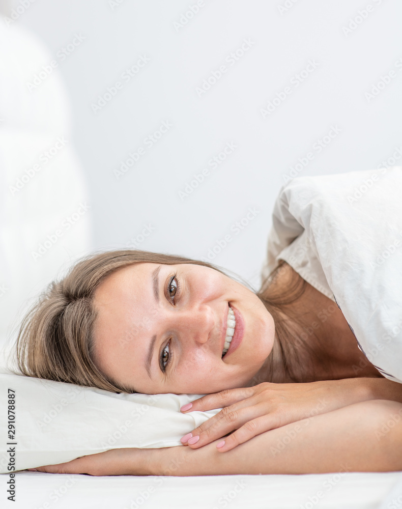 Beautiful smiling young woman lying on the bed at home Beautiful smiling young woman lying on the bed at home
