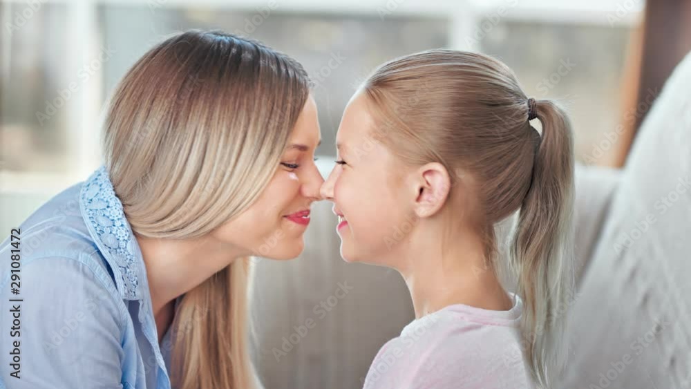 Happy family mother and cute teen daughter smiling playing touching nose relaxing together close-up Happy family mother and cute teen daughter smiling playing touching nose relaxing together close-up