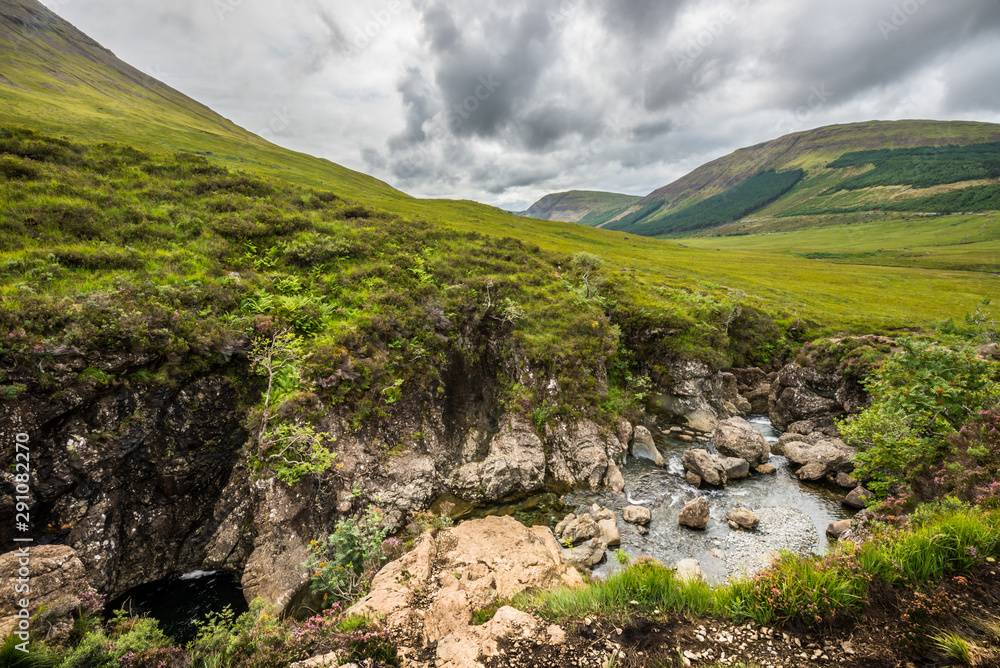 The green grass-covered hills surrounding the Fairy Pools rapids The green grass-covered hills surrounding the Fairy Pools rapids