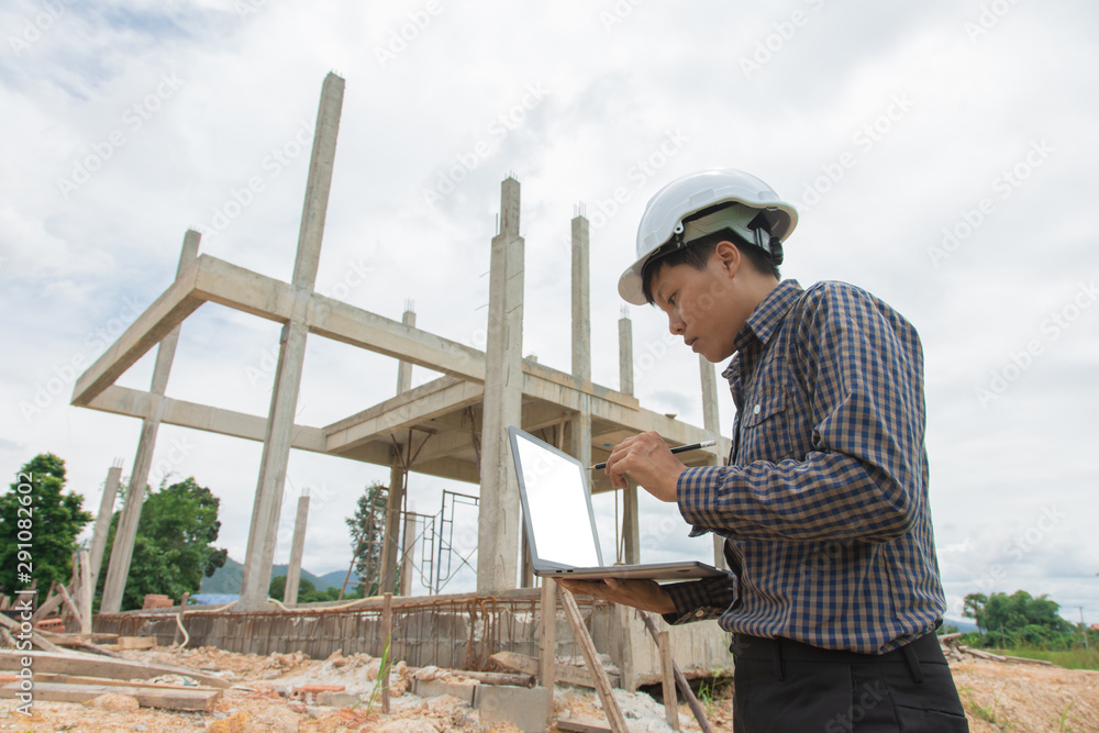 Asian manager of engineer architect in white helmet safety on construction site checking plan and project on laptop Asian manager of engineer architect in white helmet safety on construction site checking plan and project on laptop