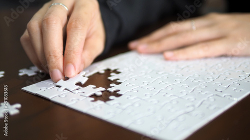 hand pick a piece of jigsaw to connect success on wooden table top selected focus