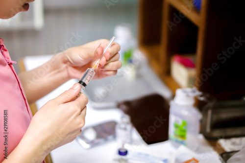 A picture of nurse hands holding a plastic syringe for preparation an injection vaccine for the patient.