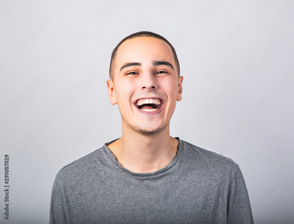 Happy fun young man laughing with wide opened mouth in casual clothing on blue background with empty copy space. Happy fun young man laughing with wide opened mouth in casual clothing on blue background with empty copy space.