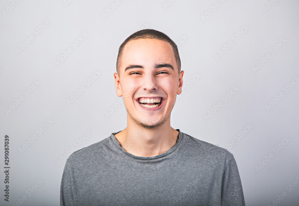 Happy fun young man laughing with wide opened mouth in casual clothing on blue background with empty copy space. Happy fun young man laughing with wide opened mouth in casual clothing on blue background with empty copy space.