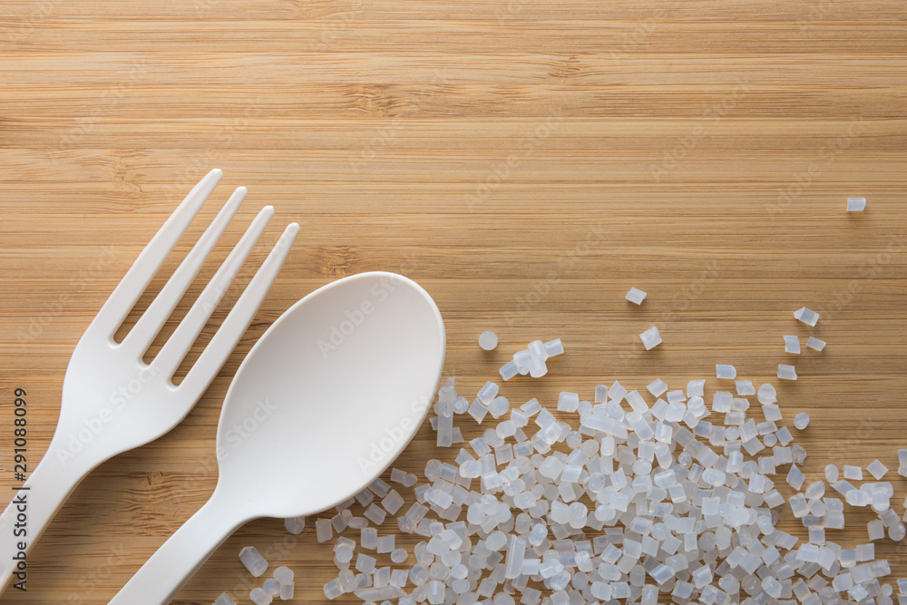 Biodegradable plastic pellets, spoon and fork made from starch and renewable sources - obrazy, fototapety, plakaty 