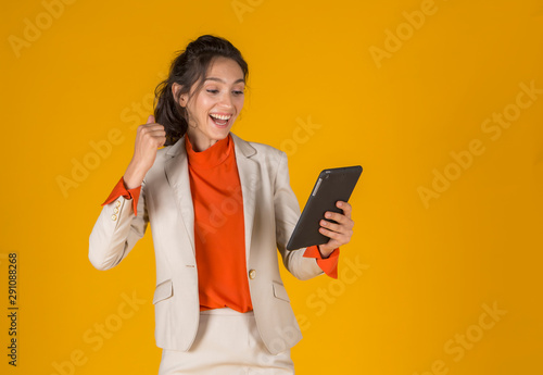 A beautiful woman company employee  holding tablet  is happy get project a yellow backgroud. photo