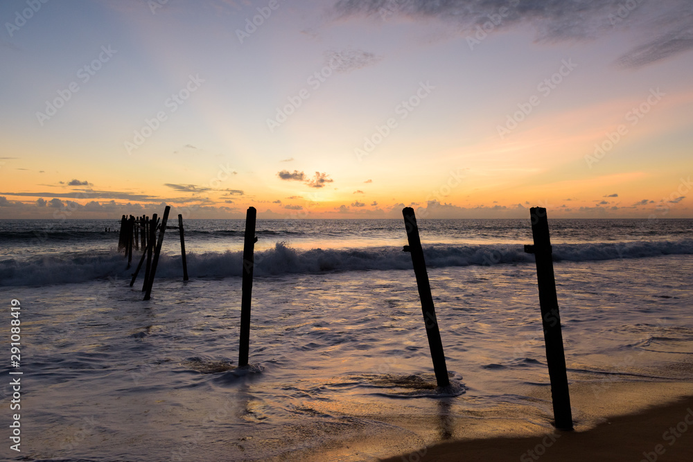Sunset on the Khao Pilai beach with old wooden bridge and lens flare