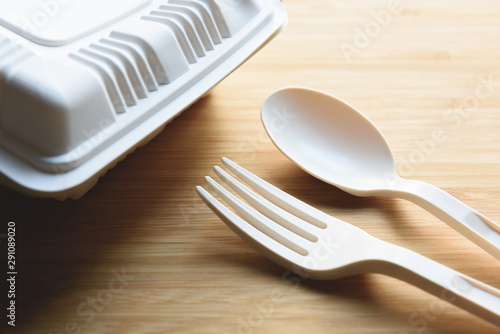 Biodegradable plastic lunch box, spoon and fork made from starch on wooden background