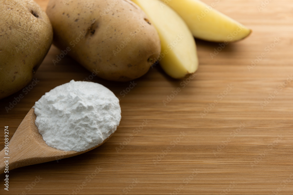 Close-up of potato starch or flour powder in wooden spoon on wooden table background Close-up of potato starch or flour powder in wooden spoon on wooden table background