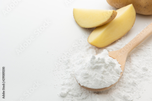 Close-up of potato starch or flour powder in wooden spoon on white background