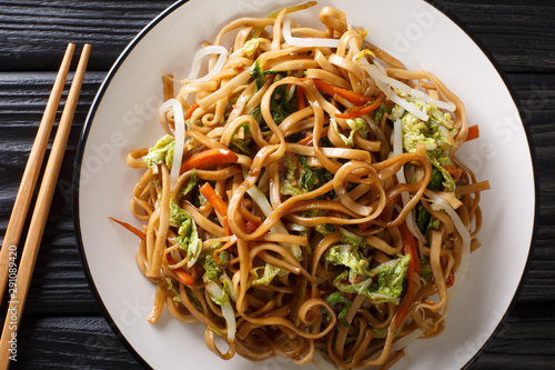 Vegetarian chow mein noodles with chinese vegetables close-up on a plate. Vertical top view