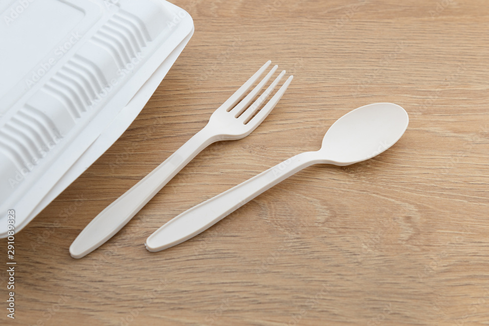 Biodegradable plastic spoon, fork and knife made from starch on wooden background Biodegradable plastic spoon, fork and knife made from starch on wooden background