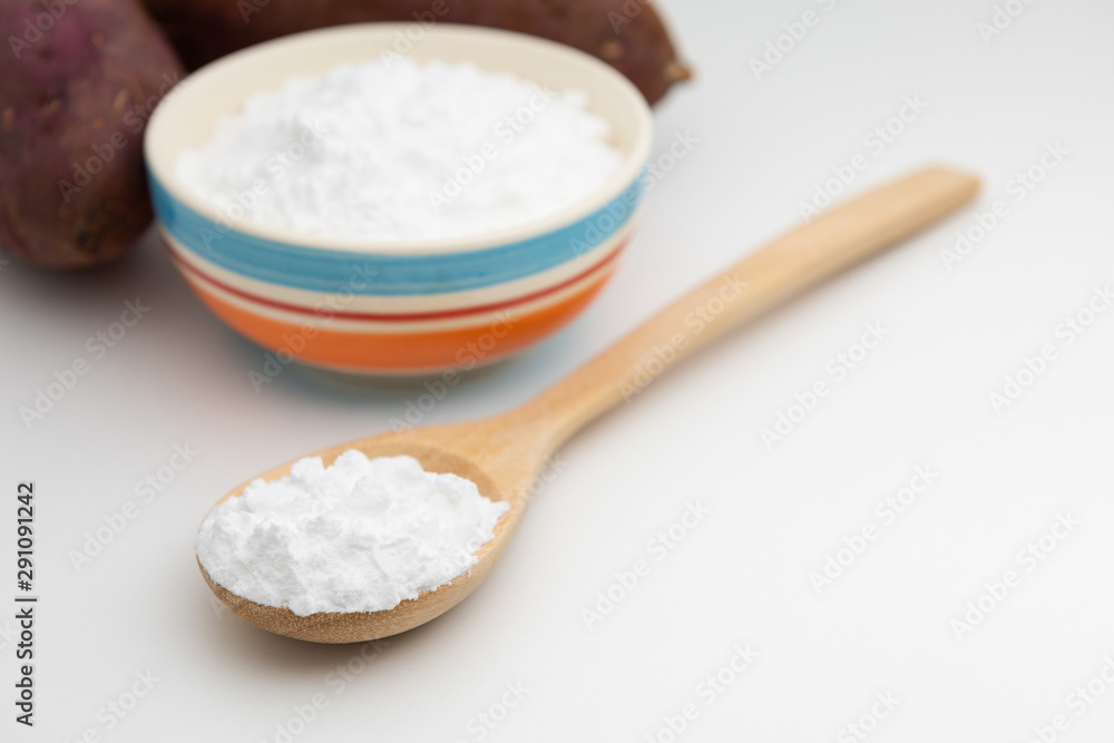 Close-up of potato starch or flour powder in wooden spoon on white background Close-up of potato starch or flour powder in wooden spoon on white background