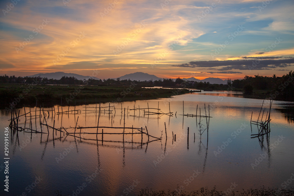 Beautiful sunset in Vietnam, fishing nets on the river, sunset on a background of mountains, Hoi An, Vietnam