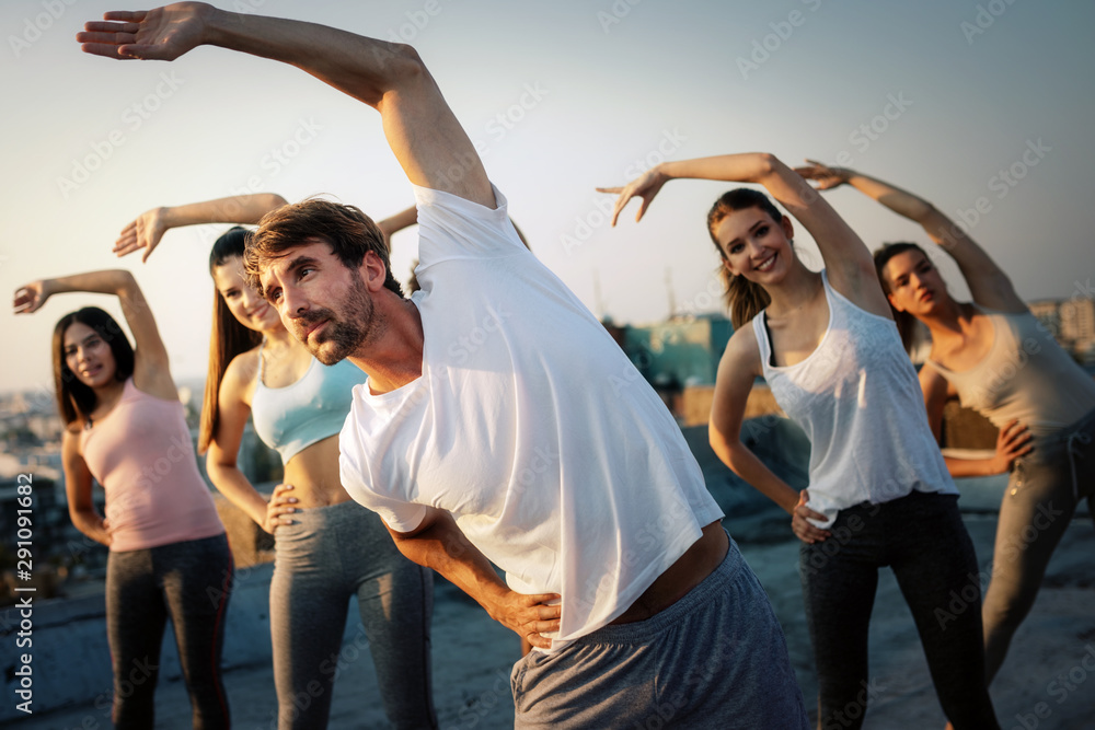 Naklejka premium Group of happy fit friends exercising outdoor in city