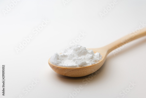 Close-up of tapioca starch or flour powder in wooden spoon on white background