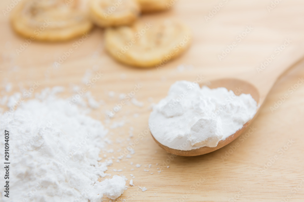 Close-up of tapioca starch or flour powder in wooden spoon and sesame butterfly pie with table wooden background Close-up of tapioca starch or flour powder in wooden spoon and sesame butterfly pie with table wooden background