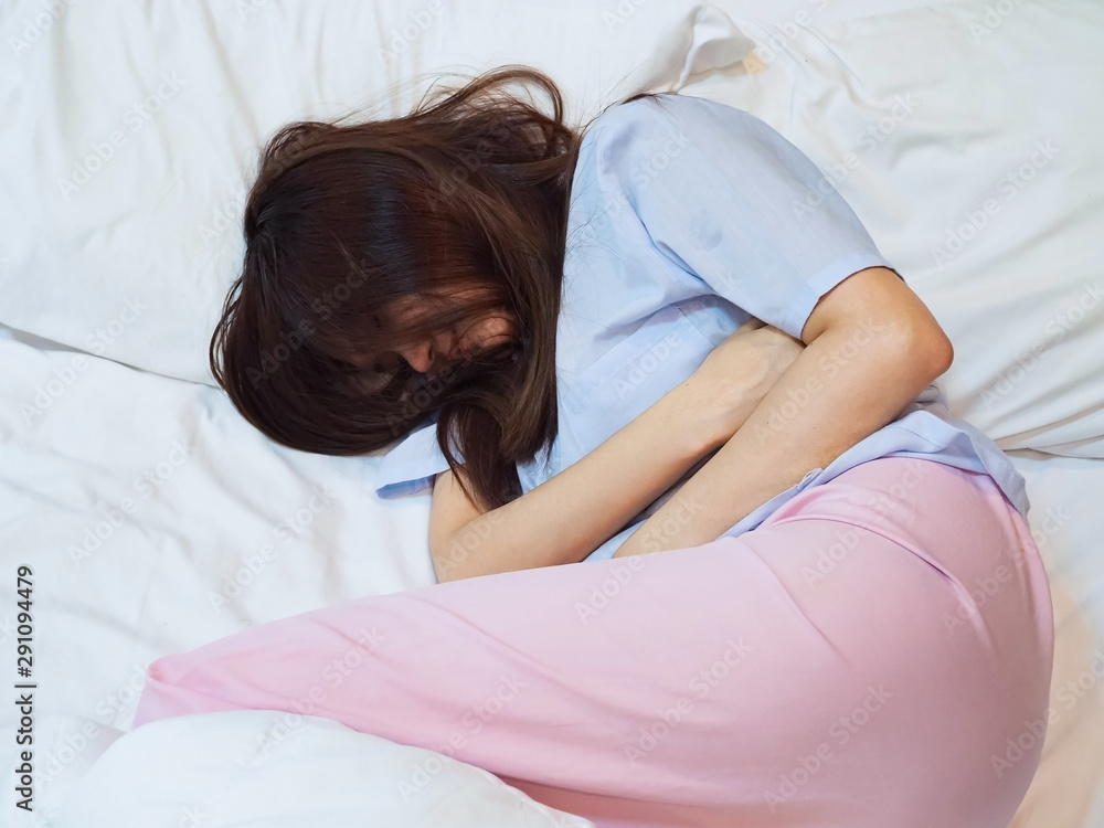 The girl is sick with a stomach ache on the bed in the morning. The girl is sick with a stomach ache on the bed in the morning.