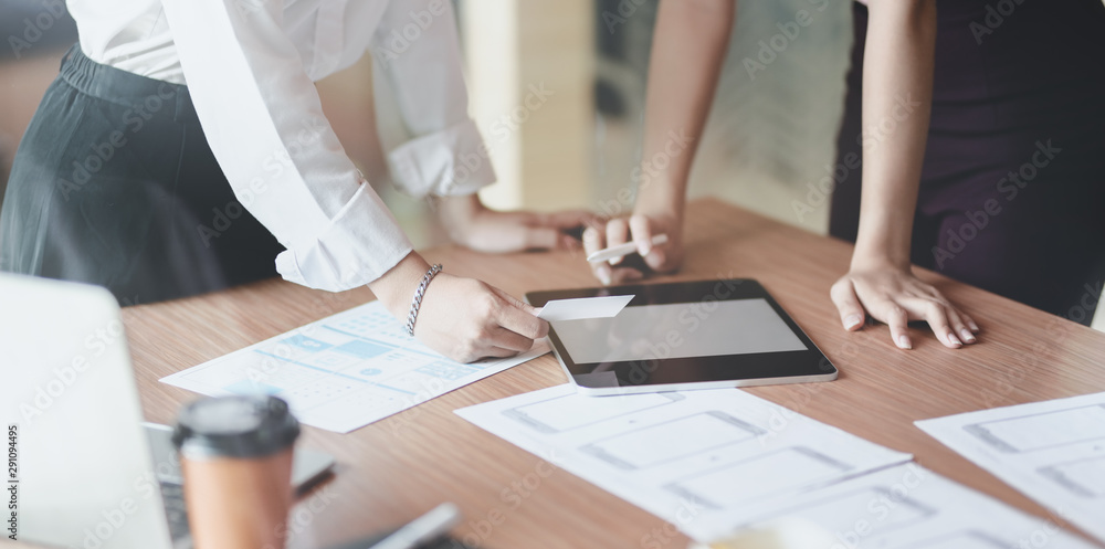 Close-up view of young UI designer brainstorming the project about UI template together while using tablet Close-up view of young UI designer brainstorming the project about UI template together while using tablet