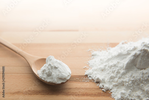 Tapet Close-up of tapioca starch or flour powder in wooden spoon on white background
