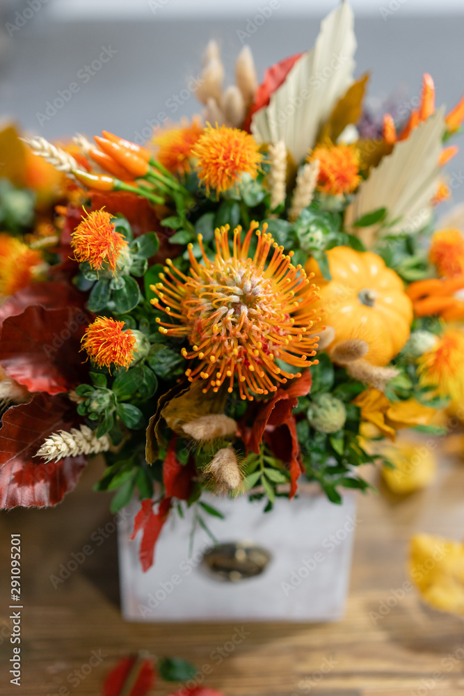Autumn bouquet of mixed flowers on wooden table. The work of the florist at a flower shop. Fresh cut flower.