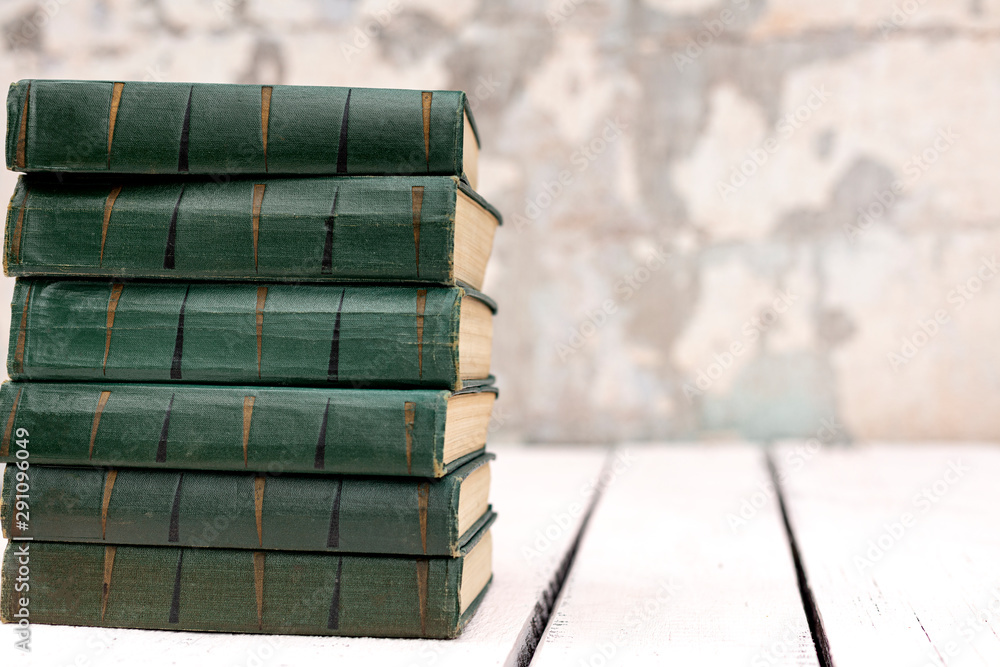 Stack of old ancient shabby books on a white wooden background.