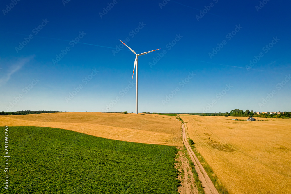 Flying above white wind turbine on field in sunny Poland Flying above white wind turbine on field in sunny Poland
