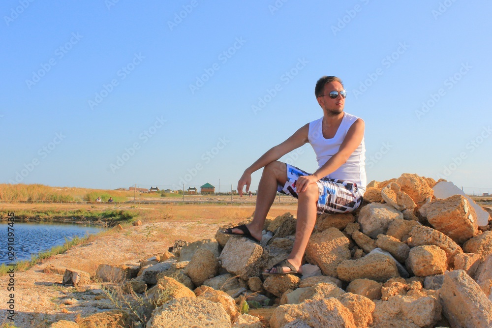 Man sitting on a rock stones with field view 