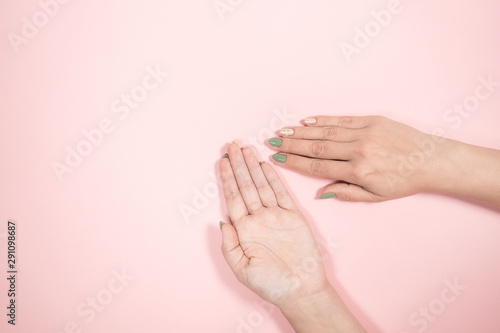 Closeup top view of two female beautiful manicured hands. Empty opened palm presenting something invisible isolated on pink background. Horizontal color photography.