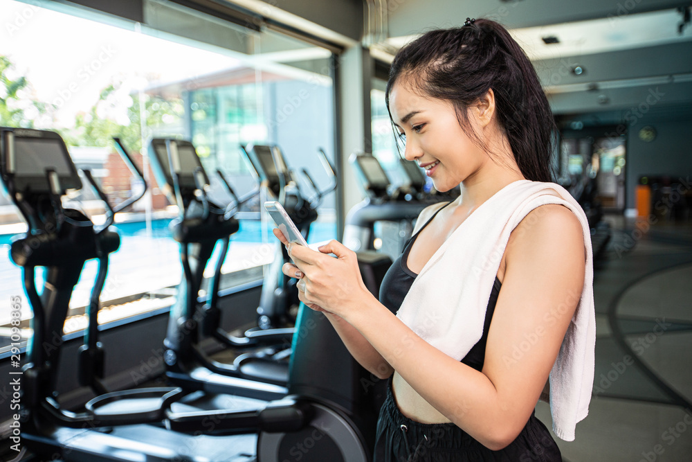 Fototapeta premium Women standing playing the phone happily in the gym.