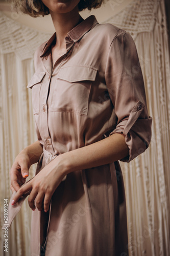 Portrait of an attractive blonde woman poses for the advertisement of a women's clothing store wearing a button-down dress
