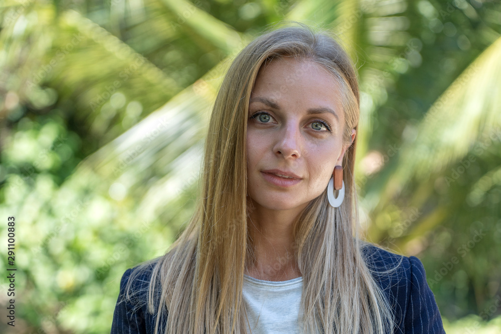 Beautiful caucasian blonde girl in a business suit in nature background. A portrait of a young business woman in tropical garden, Thailand Beautiful caucasian blonde girl in a business suit in nature background. A portrait of a young business woman in tropical garden, Thailand