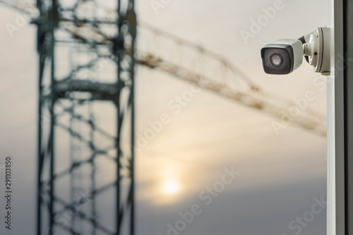 CCTV or surveillance camera on blurred construction crane dusk sky background
