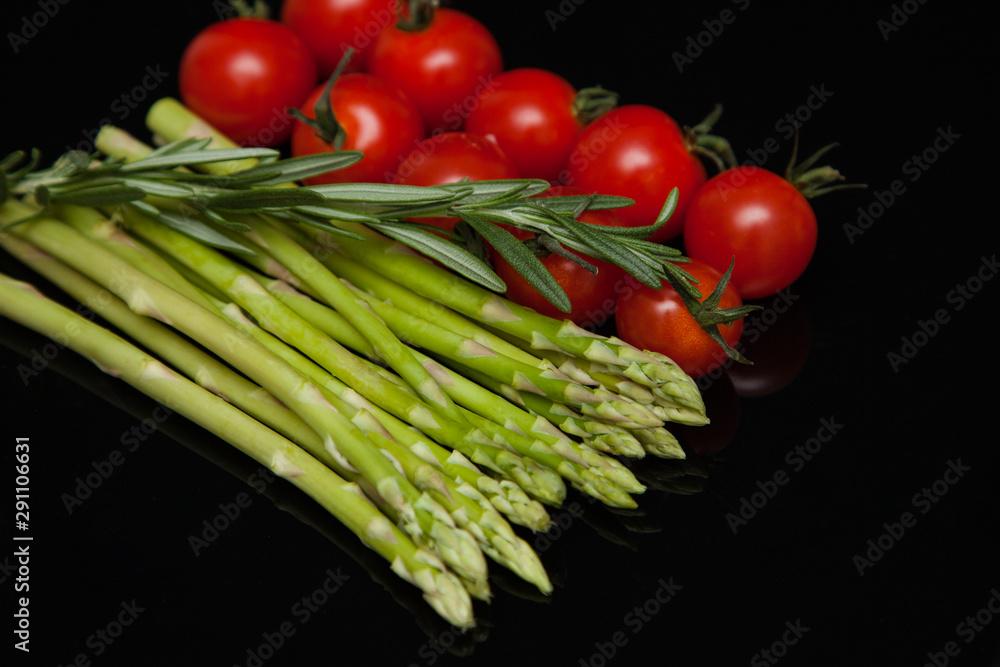 asparagus with tomatoes on a mirrored black table asparagus with tomatoes on a mirrored black table