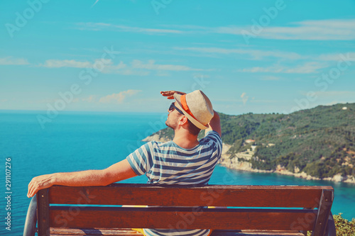 Attractive man sitting on the bench and enjoying on the tropical beach. Summer concept. © Kitja
