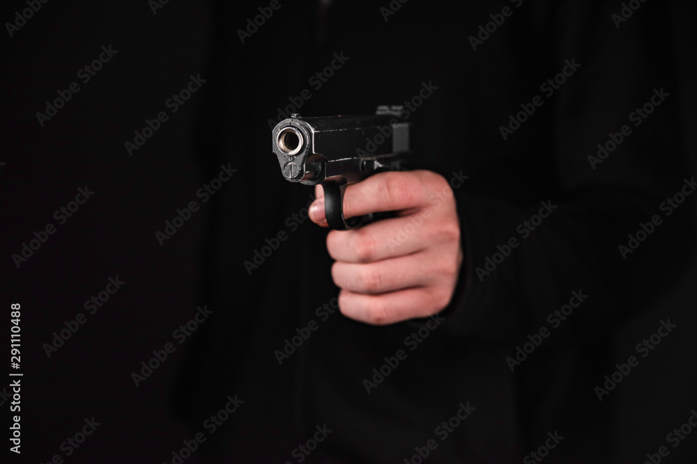 Gun in hand on black background. The threat of a firearm during a robbery on a dark street. Assault with a semiautomatic weapon. Gun in hand on black background. The threat of a firearm during a robbery on a dark street. Assault with a semiautomatic weapon.
