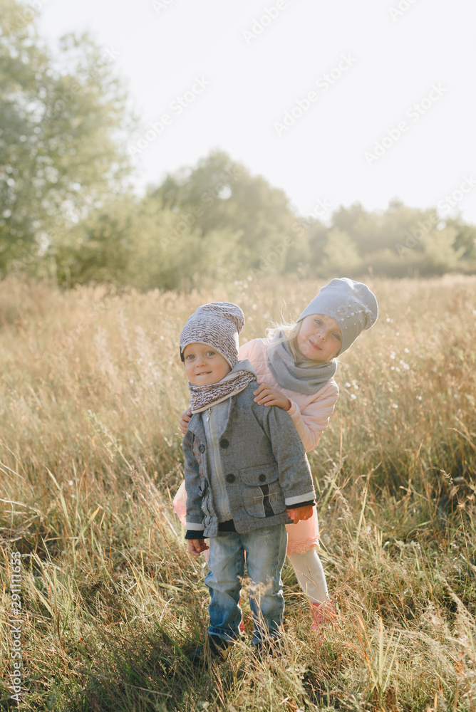 little girl with little brother in the autumn on the nature in the park little girl with little brother in the autumn on the nature in the park