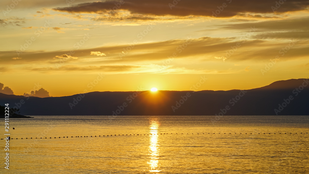Yellow-orange sunset on the Adriatic. The sun is hiding behind the mountains of Istria Yellow-orange sunset on the Adriatic. The sun is hiding behind the mountains of Istria