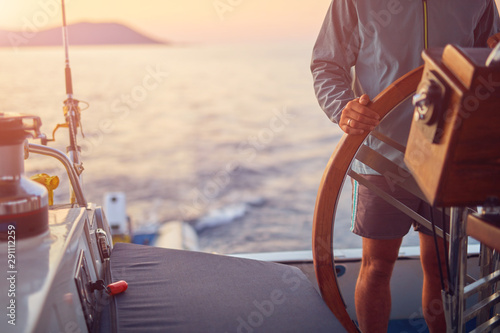 Sailor using wheel to steer rudder on a sailing boat. photo