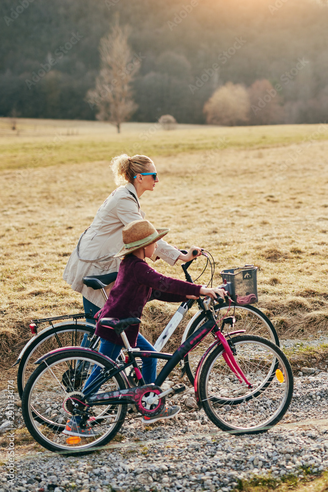Obraz premium Mother and daughter with bicycles on countryside.