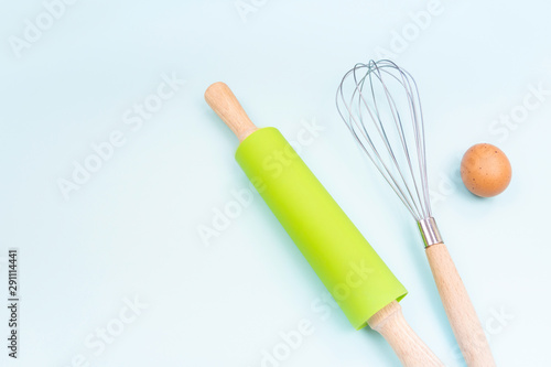 Kitchen utensils and baking accessories on blue background with copy space. Rolling pin and whisk for cooking. Set for mock ups and bakery design. Flat lay.