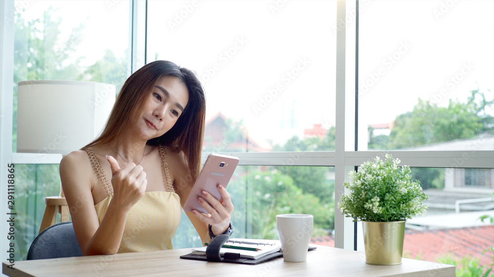 Young beautiful Asian woman enjoying a relaxing moment working and using mobile phone as mobile smart payment to pay for a coffee in the coffeeshop on a bright sunny day Young beautiful Asian woman enjoying a relaxing moment working and using mobile phone as mobile smart payment to pay for a coffee in the coffeeshop on a bright sunny day