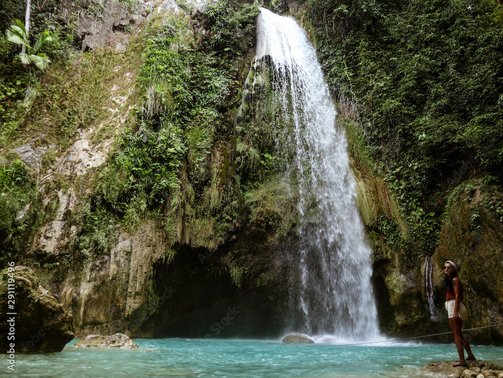 Naklejka premium Woman alone in deep forest waterfall from mountain gorge at hidden tropical jungle in Cebu Island in Philippines