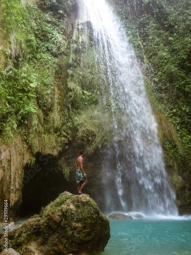 Epic man alone in deep forest waterfall from mountain gorge at hidden tropical jungle in Cebu Island in Philippines