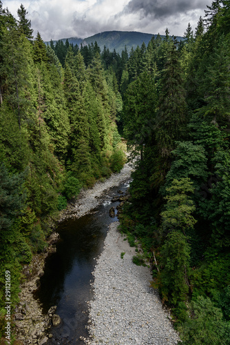 Capilano River, Vancouver, Canada, running through a lush, wooded valley, with mountains in the background. The day is cloudy.