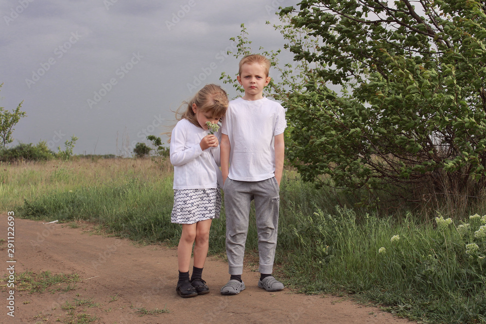 Little children in white clothes stand against a dark stormy sky. Little children in white clothes stand against a dark stormy sky.
